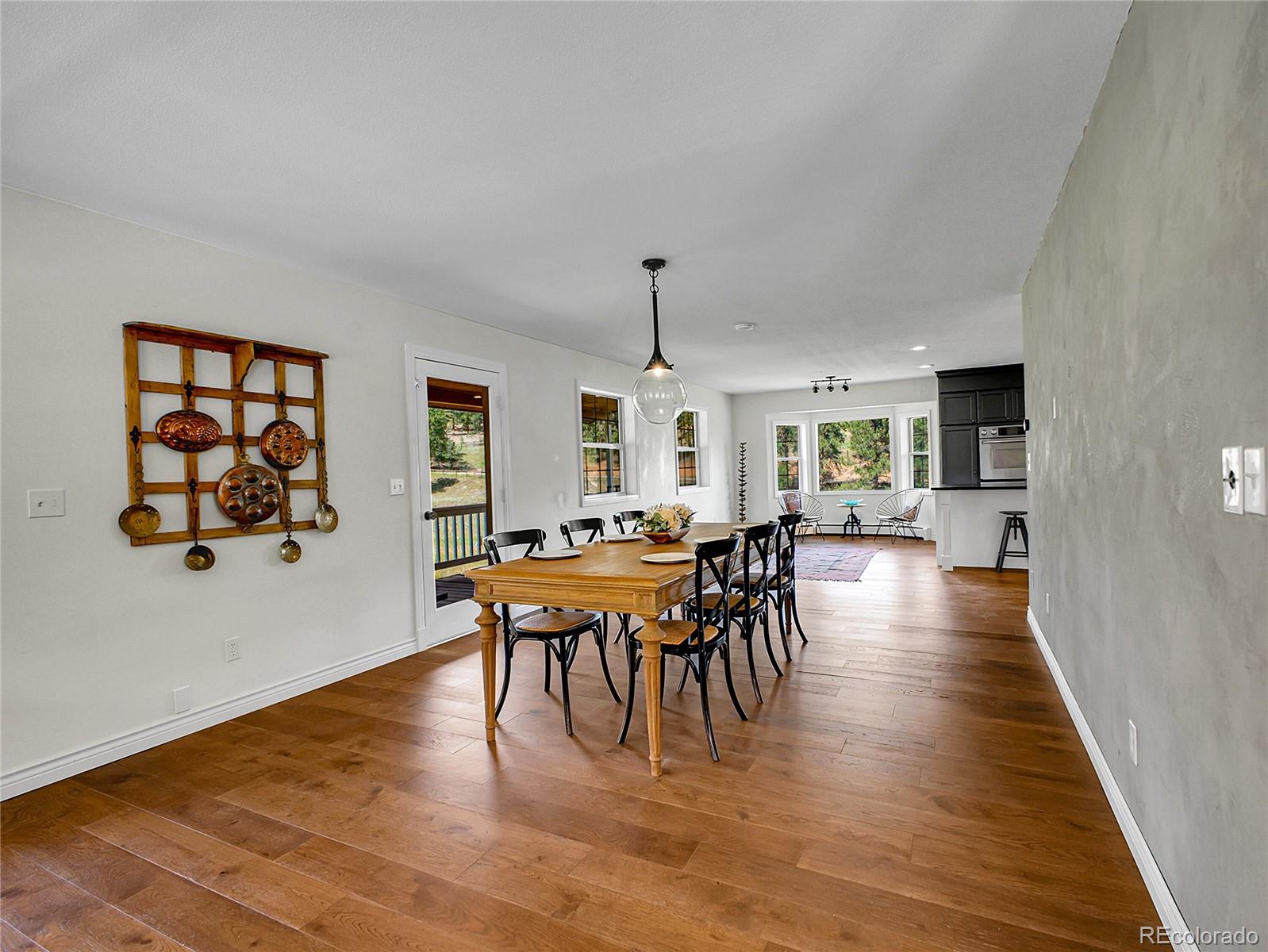 2635 Nova Road Pine, CO 80470 - Photo 16 of 45 a dining room with furniture wooden floor a rug and a painting
