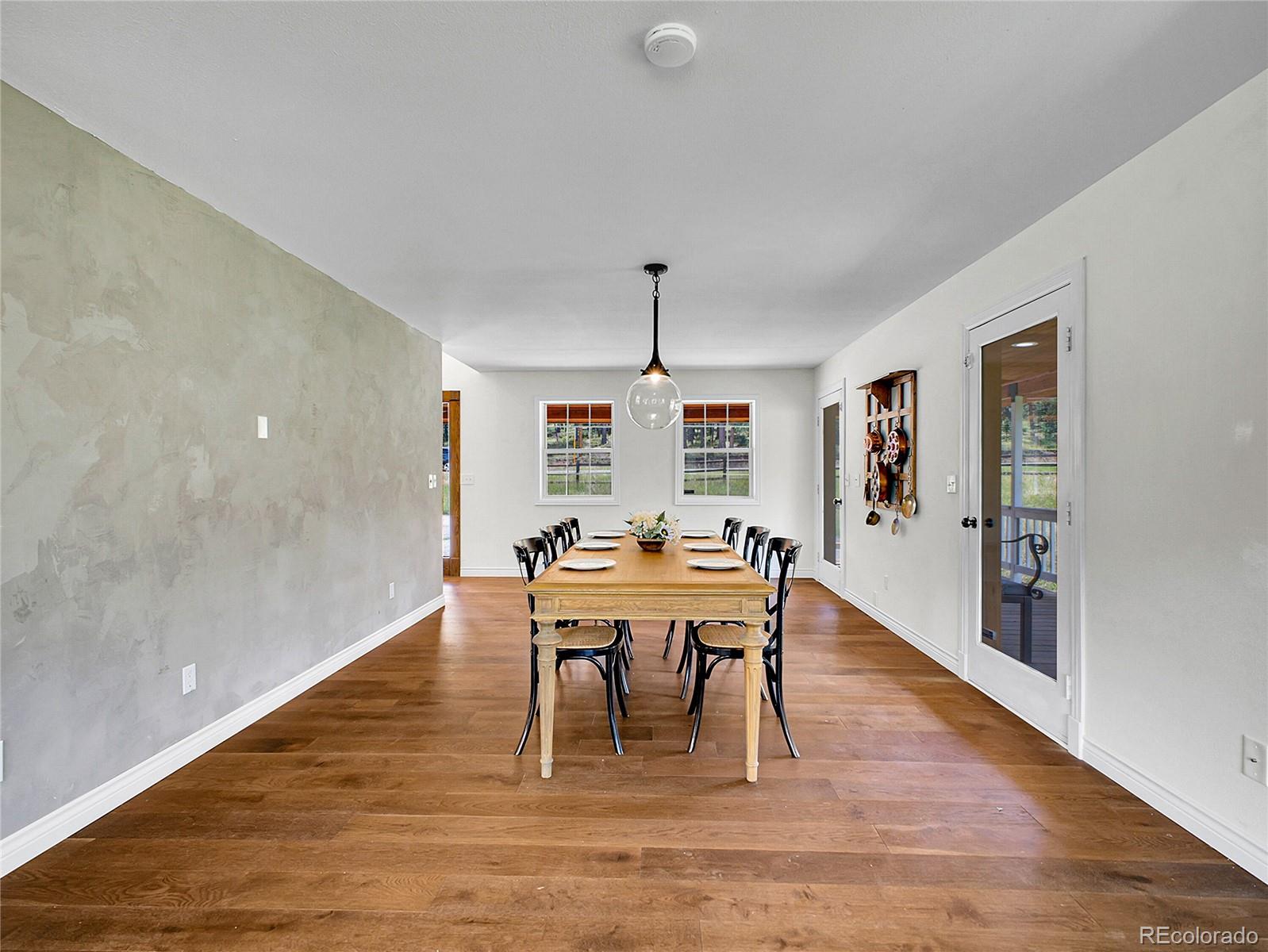 2635 Nova Road Pine, CO 80470 - Photo 24 of 45 a dining room with wooden floor a chandelier a wooden table and chairs