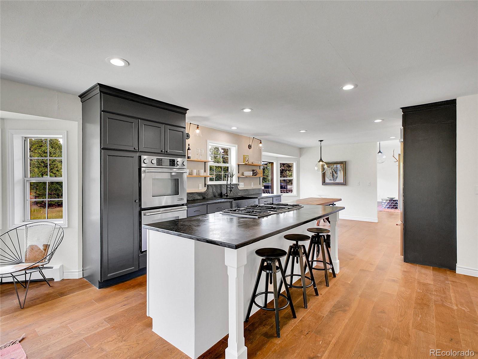 2635 Nova Road Pine, CO 80470 - Photo 7 of 45 a kitchen with stainless steel appliances kitchen island granite countertop a refrigerator a stove a sink a dining table and chairs with wooden floor