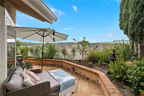 a view of a patio with couches table and chairs under an umbrella with a small yard