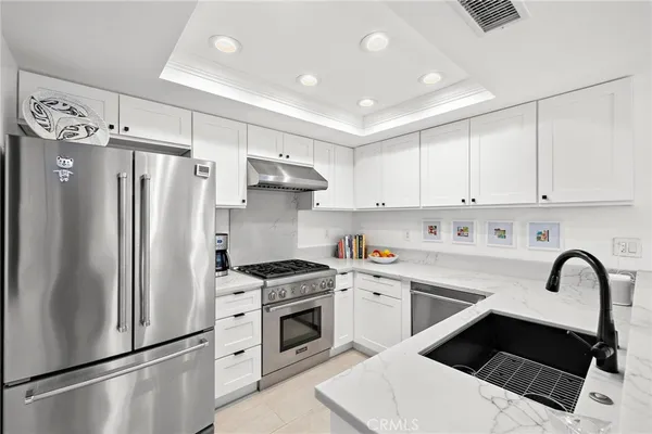 a kitchen with stainless steel appliances a refrigerator sink and white cabinets