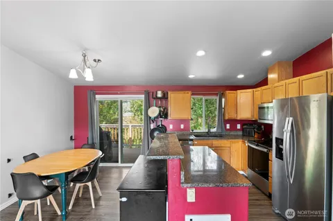 a kitchen with stainless steel appliances granite countertop a kitchen island hardwood floor and a large window