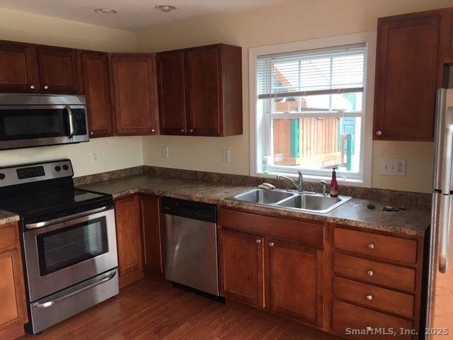 38 B Prospect Street Stonington, CT 06379 - Photo 6 of 13 a kitchen with granite countertop wooden cabinets a sink and a stove with wooden floor