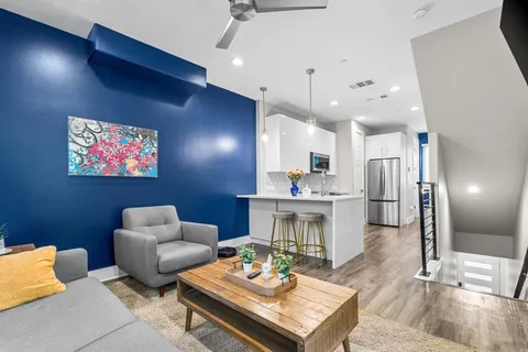 a living room with furniture kitchen view and a chandelier