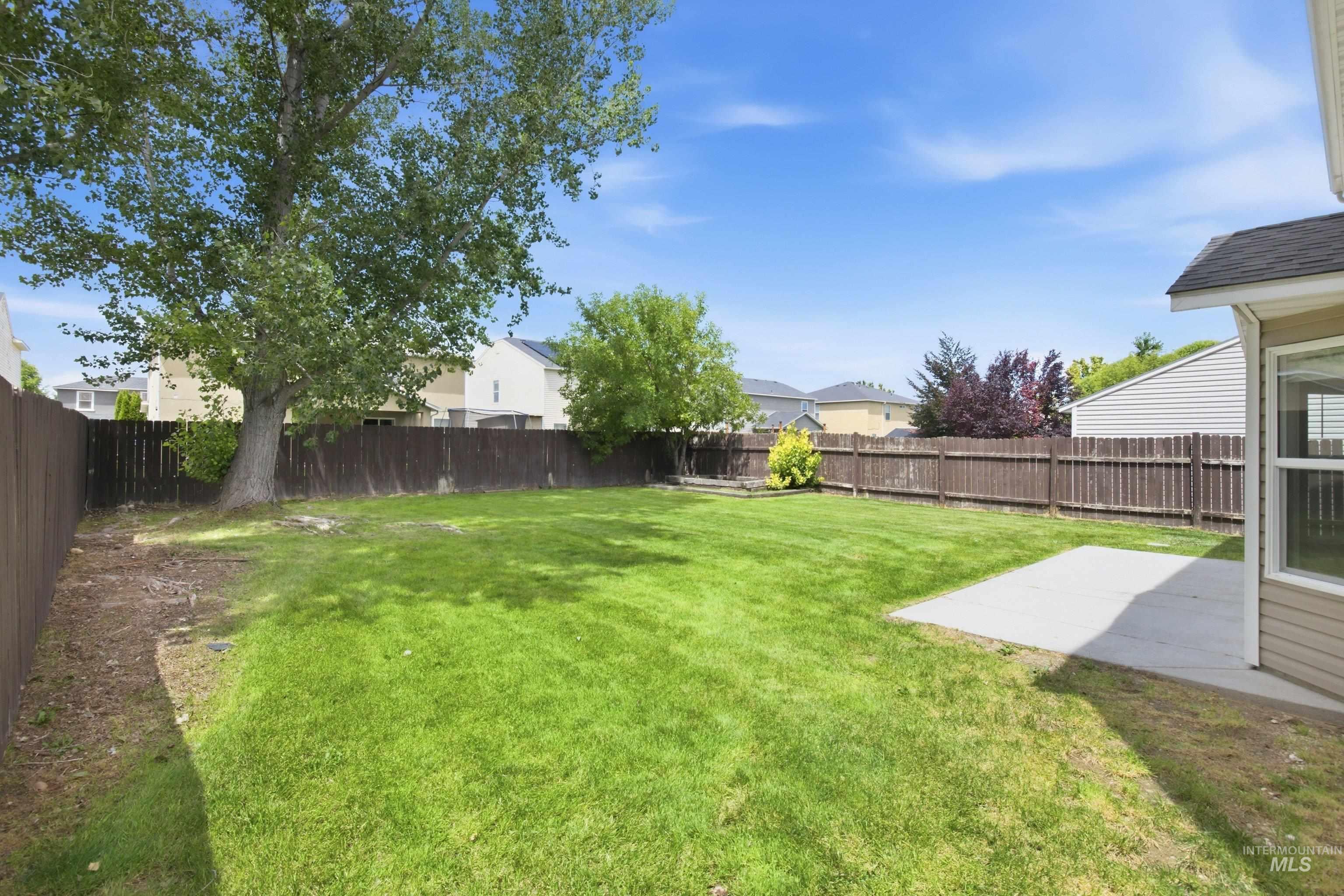 16759 Abram Avenue Caldwell, ID 83607 - Photo 28 of 33 Expansive backyard featuring a lush green lawn, mature trees, and a concrete patio