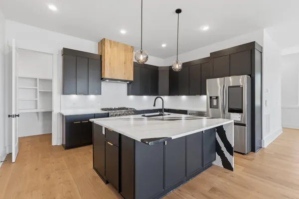 a kitchen with kitchen island granite countertop a sink appliances and cabinets