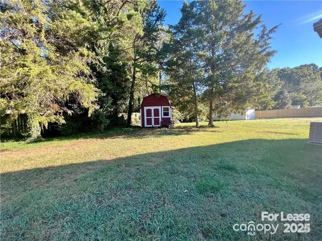 a view of yard with swimming pool and trees in the background