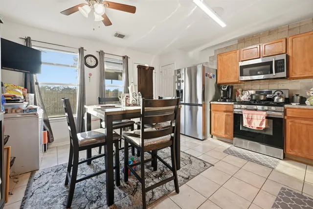 a kitchen with stainless steel appliances granite countertop a stove top oven a sink a dining table and chairs with wooden floor