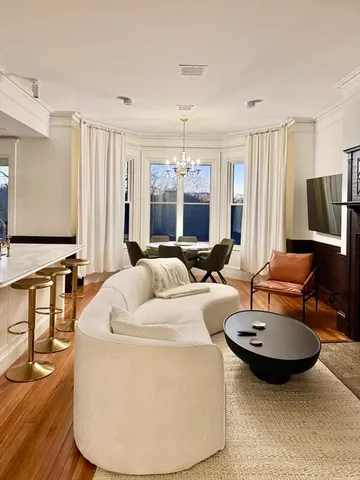 a living room with furniture a large window and a chandelier