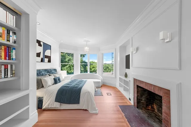 a spacious bedroom with a bed a fireplace and a book shelf