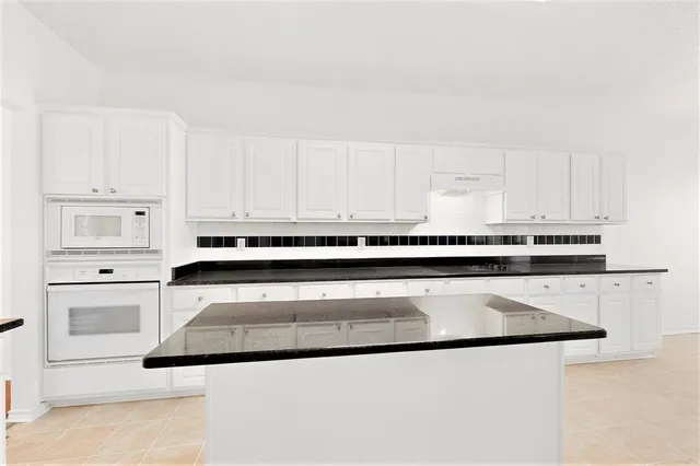 a kitchen with granite countertop white cabinets and stainless steel appliances