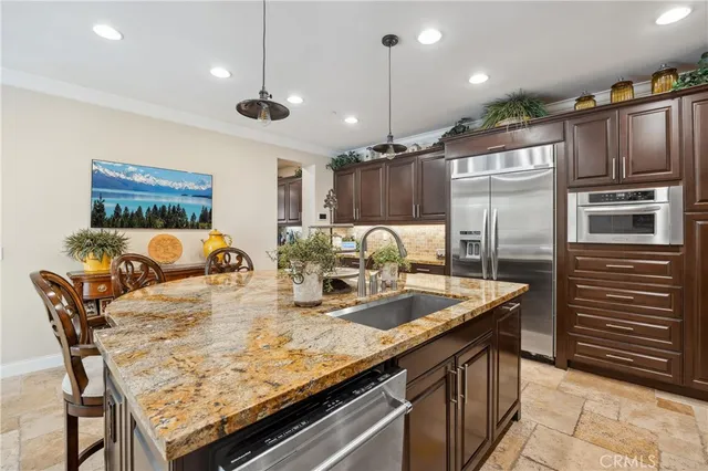 a kitchen with stainless steel appliances a dining table chairs refrigerator and cabinets