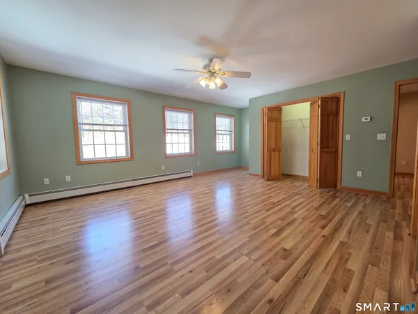 a view of an empty room with window and wooden floor