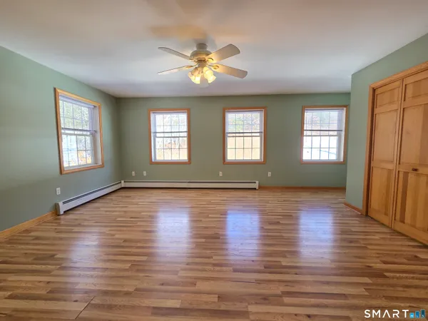 a view of an empty room with window and wooden floor