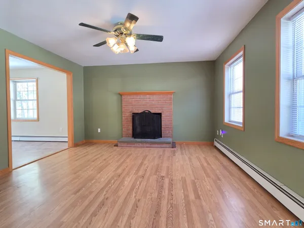 a view of an empty room with a window and wooden floor