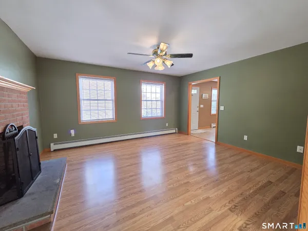 a view of an empty room with window and wooden floor