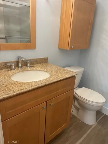a bathroom with a granite countertop toilet sink and mirror