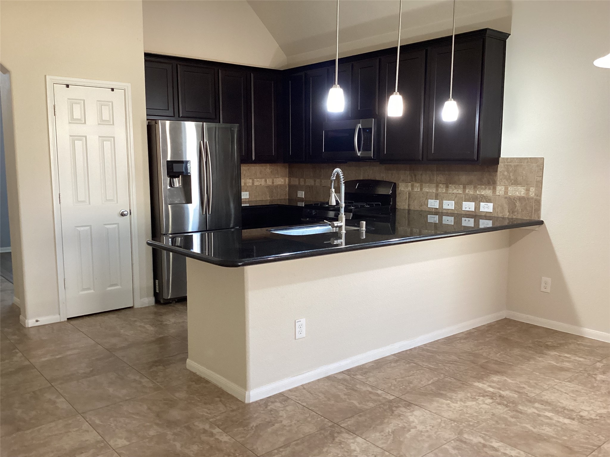 20122 Graphite Canyon Court Richmond, TX 77407 - Photo 12 of 27 Experience the charm of this open kitchen, featuring sleek dark cabinetry, stainless steel appliances, and elegant pendant lighting over a spacious island ideal for entertaining.