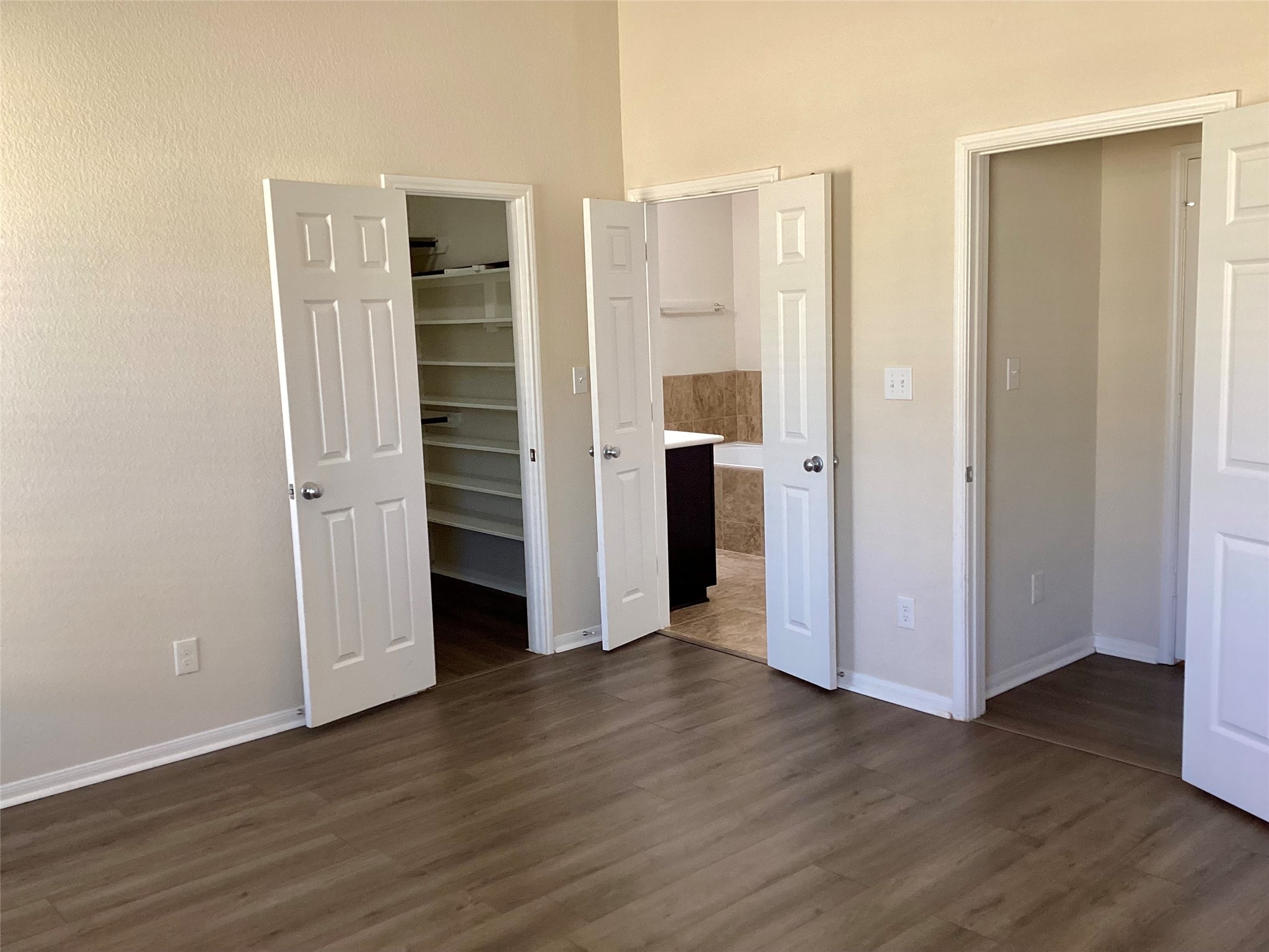 20122 Graphite Canyon Court Richmond, TX 77407 - Photo 17 of 27 Experience the charm of this room with elegant wood-style flooring and soothing neutral walls. Three doorways lead to a bathroom, closet, and bonus space, while open shelves offer practical storage.