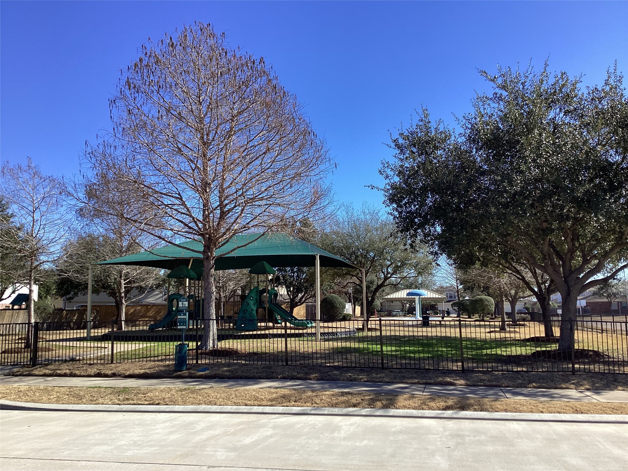 20122 Graphite Canyon Court Richmond, TX 77407 - Photo 25 of 27 Charming fenced playground with slides and shaded areas, nestled in a tree-lined residential neighborhood—an ideal family-friendly outdoor retreat.