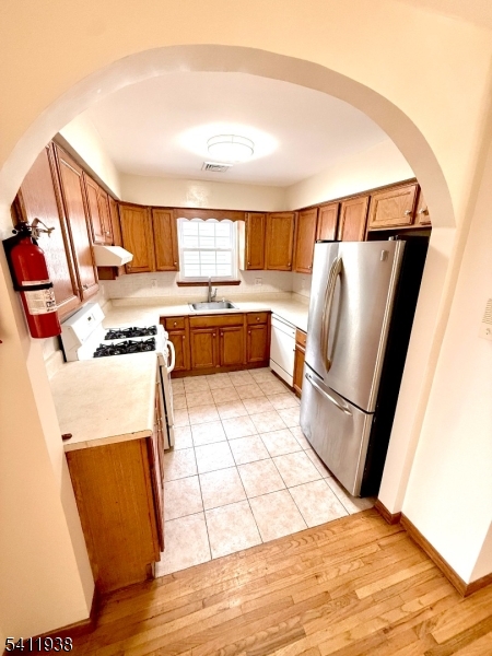 213 Palmer Street, Unit 2 Elizabeth, NJ 07202 - Photo 11 of 28 a kitchen with a refrigerator a stove a sink and a dining table with wooden floor