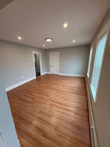 a view of an empty room with wooden floor and stairs