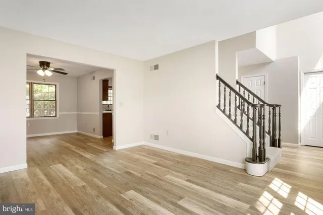 a view of an empty room with wooden floor and stairs