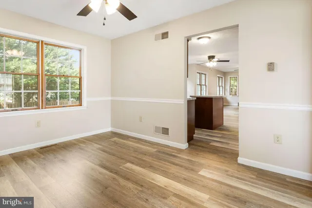 an empty room with wooden floor cabinet and windows