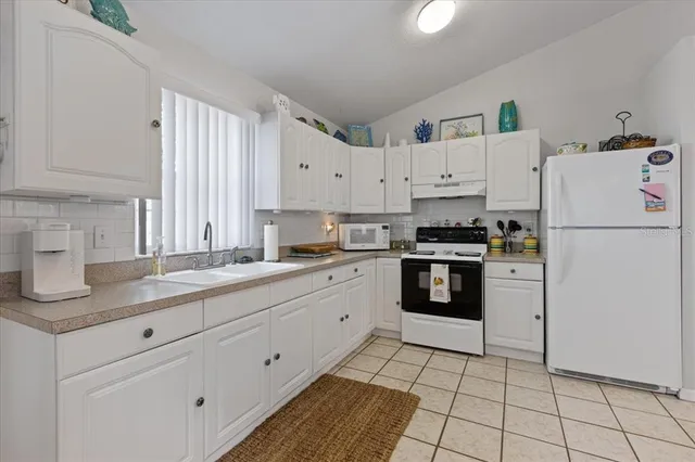 a kitchen with granite countertop white cabinets and white appliances