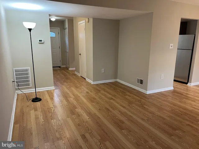 a view of an empty room with wooden floor and a sink