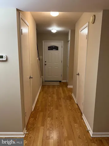 a view of a hallway with wooden floor and a bathroom