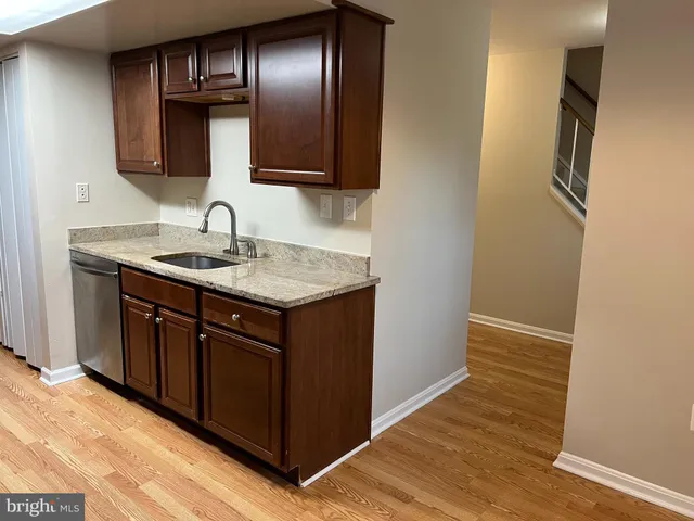 a kitchen with a granite countertop sink and a wooden floor