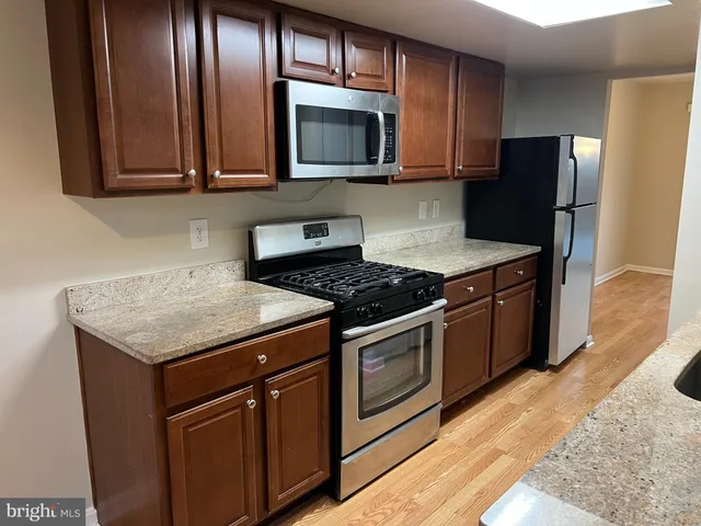a kitchen with granite countertop wooden cabinets and stainless steel appliances