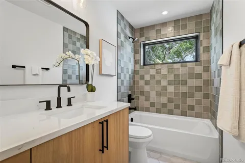 a bathroom with a sink a toilet a mirror a vanity a bathtub and shower