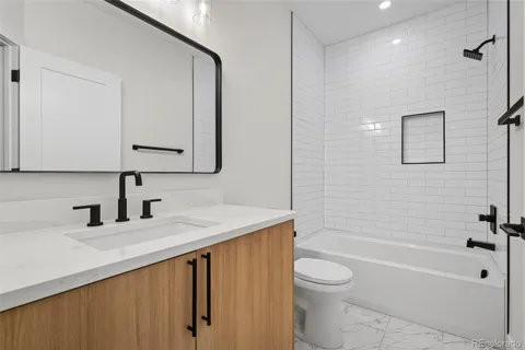 a bathroom with a granite countertop sink a toilet and shower