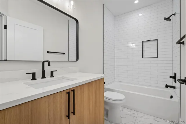 a bathroom with a granite countertop sink a toilet and shower