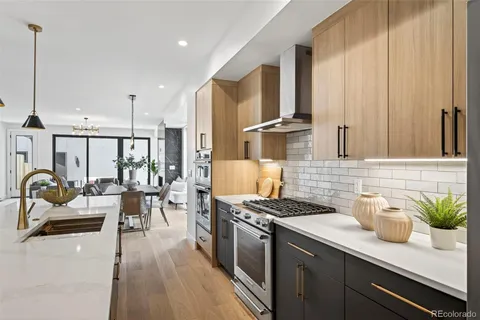 a kitchen with stainless steel appliances granite countertop a sink a stove and a wooden floor