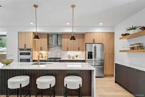 a kitchen with stainless steel appliances a dining table chairs refrigerator and sink
