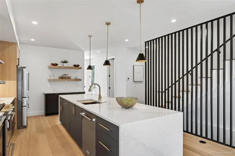 a kitchen with stainless steel appliances granite countertop a sink dishwasher a refrigerator white cabinets and wooden floor