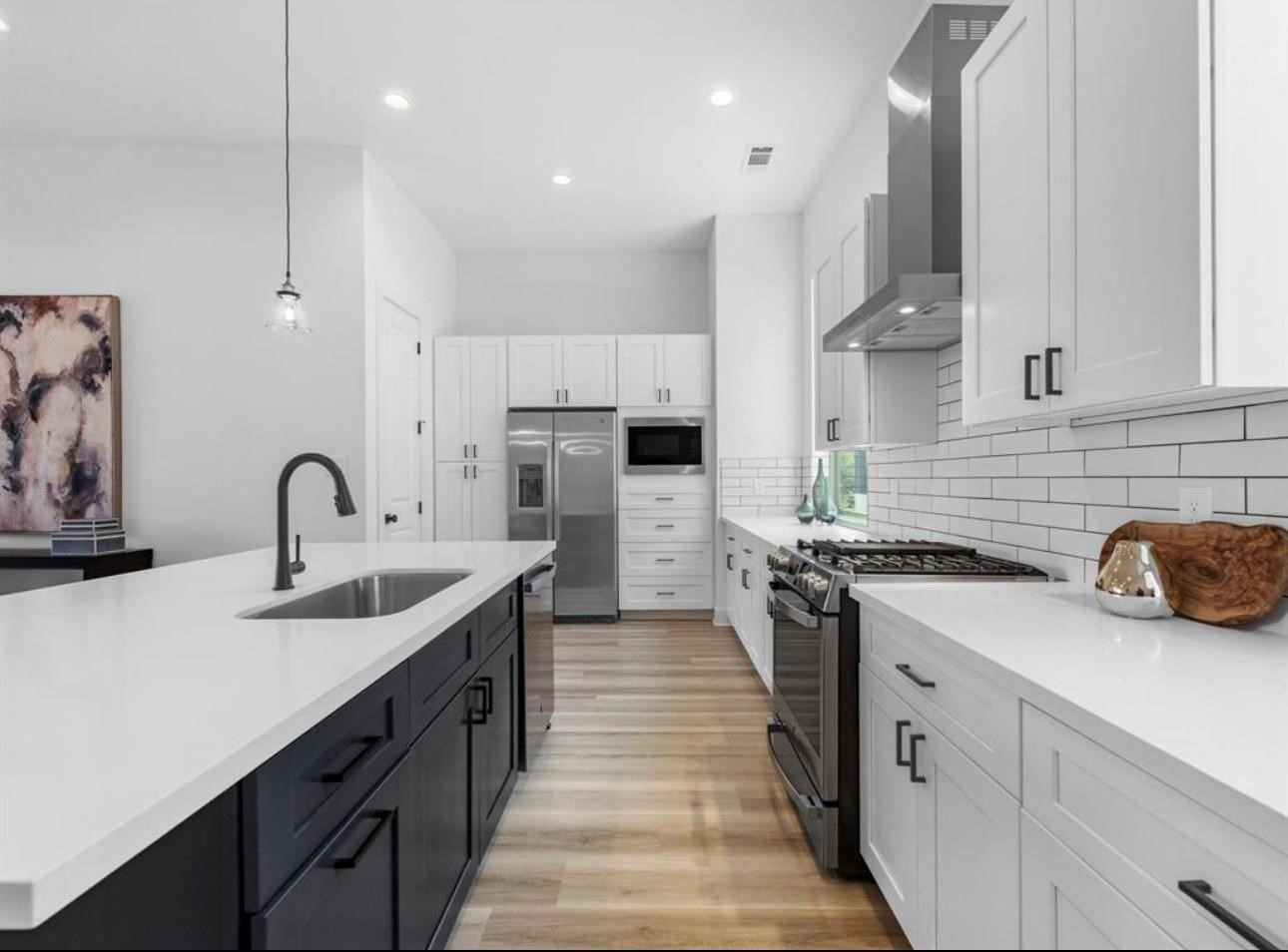 5910 Val Verde Street Houston, TX 77057 - Photo 7 of 21 a kitchen with stainless steel appliances a sink dishwasher a stove top oven a refrigerator with wooden cabinets and floor