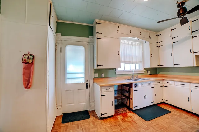 a kitchen that has a lot of cabinets in it and wooden floors