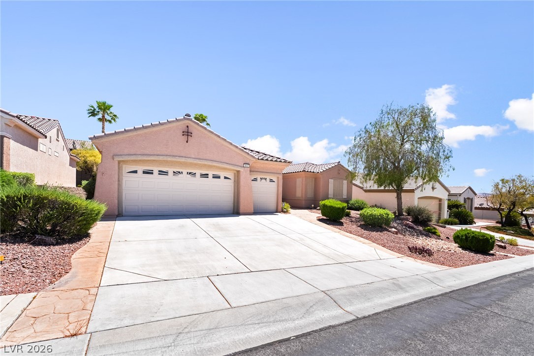 3033 Hartsville Road Henderson, NV 89052 - Photo 4 of 41 A gracefully sloped driveway leads to a welcoming stucco home with well-maintained desert landscaping.