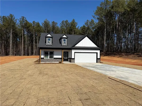a front view of a house with yard and trees in the background