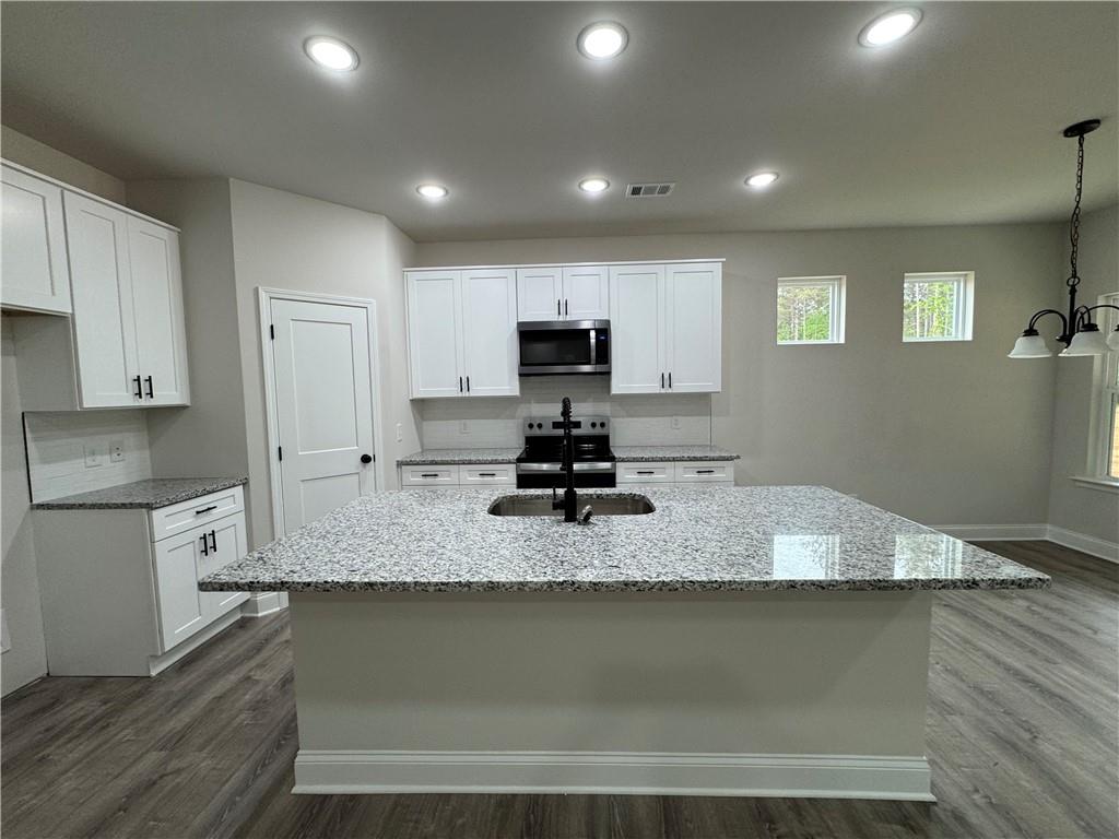 2113 North Hicks Road Toccoa, GA 30577 - Photo 8 of 28 a kitchen with kitchen island granite countertop a sink a stove counter space and cabinets