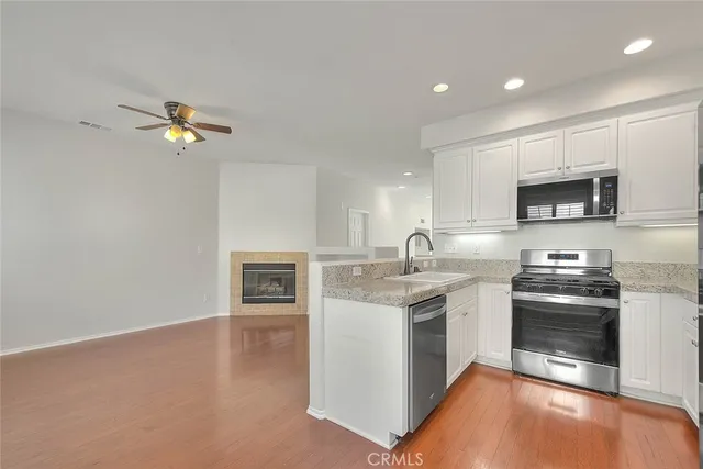 a kitchen with stainless steel appliances granite countertop a sink dishwasher a stove and a microwave oven with cabinets