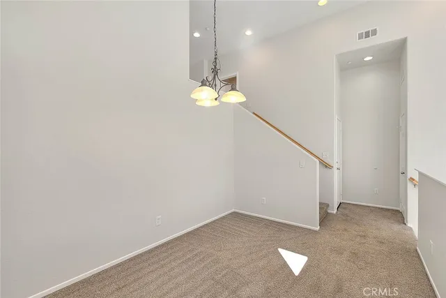 an empty room with wooden floor chandelier fan and windows