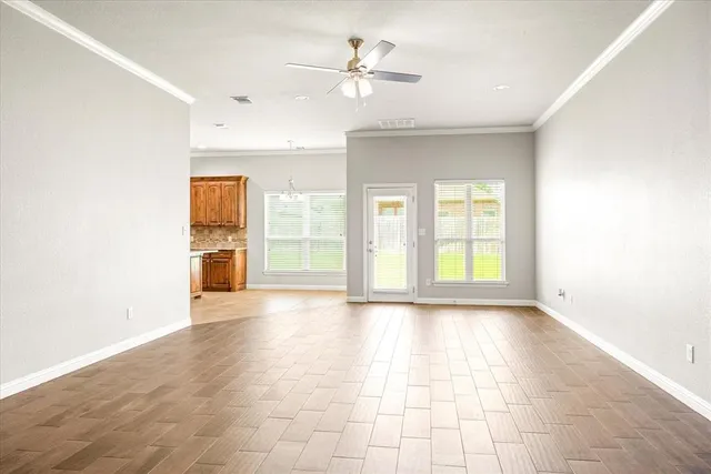 a view of an empty room with a window and a kitchen