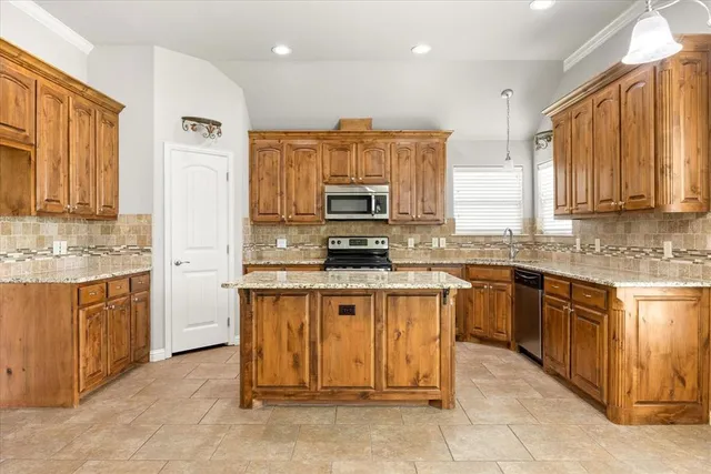 a kitchen with stainless steel appliances granite countertop a stove top oven a sink dishwasher and a refrigerator