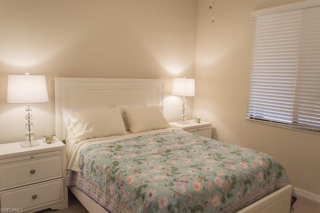 9566 Trevi Court, Unit 4943 Naples, FL 34113 - Photo 12 of 33 a bedroom with a bed and a lamp