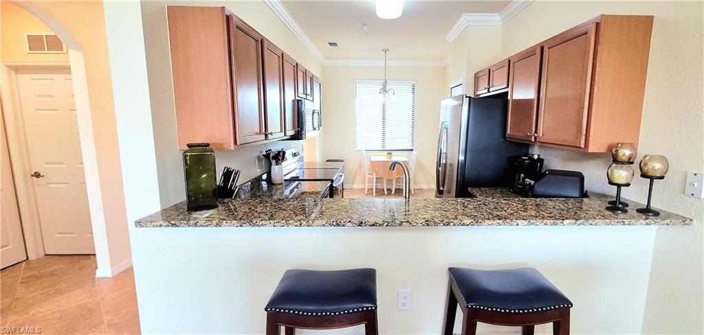 9566 Trevi Court, Unit 4943 Naples, FL 34113 - Photo 14 of 47 a kitchen with stainless steel appliances granite countertop a sink and a refrigerator